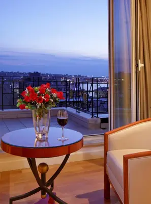 a table with a vase of flowers and a glass of wine at Piraeus Theoxenia Hotel in Piraeus