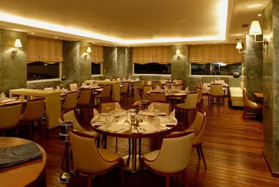a restaurant with tables and chairs in a room at Piraeus Theoxenia Hotel in Piraeus