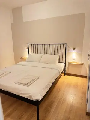 a bedroom with a bed with white sheets and a wooden floor at SIS Urban Apartments in Athens