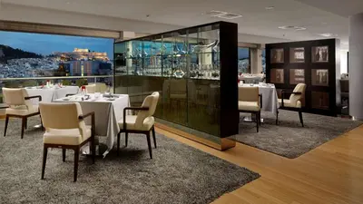 a restaurant with white tables and chairs and a view at Athenaeum Intercontinental by IHG in Athens