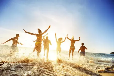 a group of people running in the water on the beach at Athenaeum Intercontinental by IHG in Athens