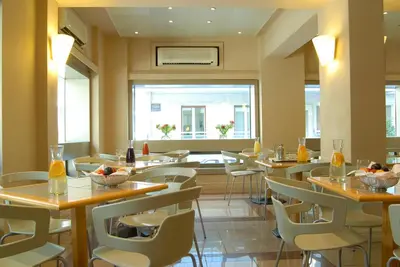 a restaurant with tables and chairs and a window at Philippos Hotel in Athens