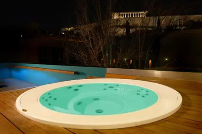 a hot tub on a deck at night at Herodion Hotel in Athens