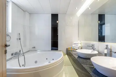 a white bathroom with a tub and a sink at Oasis Hotel Apartments in Athens