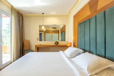 a bedroom with a large white bed and a desk at Oasis Hotel Apartments in Athens
