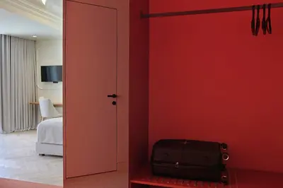 a room with a red wall and a door with a suitcase at DWELL - Elegant City Stay in Athens