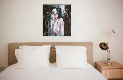 a bed with white pillows and a painting on the wall at Modern 55m2 Centrally located flat in Athens