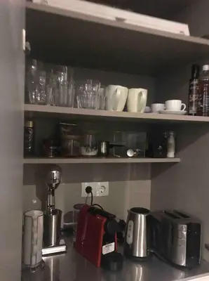 a kitchen counter with a coffee maker and cups on shelves at Modern 55m2 Centrally located flat in Athens