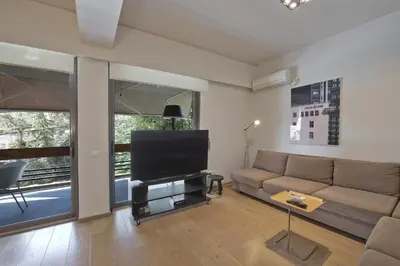 a living room with a couch and a flat screen tv at Sea Breeze Spacious Apt near Vouliagmeni Beach in Athens