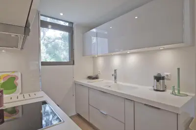 a white kitchen with a sink and a mirror at Sea Breeze Spacious Apt near Vouliagmeni Beach in Athens