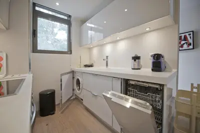 a white kitchen with a sink and a dishwasher at Sea Breeze Spacious Apt near Vouliagmeni Beach in Athens
