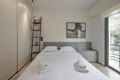 a white bedroom with a large white bed and a window at Sea Breeze Spacious Apt near Vouliagmeni Beach in Athens