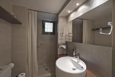 a bathroom with a white sink and a shower at Sea Breeze Spacious Apt near Vouliagmeni Beach in Athens