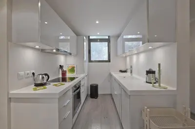 a white kitchen with white counters and white cabinets at Sea Breeze Spacious Apt near Vouliagmeni Beach in Athens