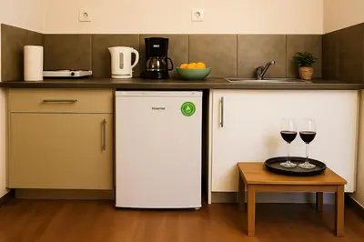 a kitchen with a white refrigerator and two glasses of wine at Metropolis A2 - Υπέροχη ανακαινισμένη Σουίτα in Athens