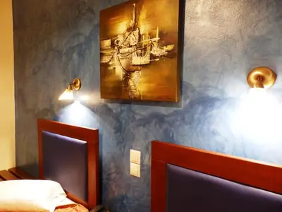 a bedroom with two beds and a painting on the wall at Pergamos Hotel in Athens