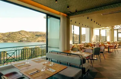 a restaurant with tables and chairs and large windows at Zeus Dolce by Wyndham Athens in Vravrona
