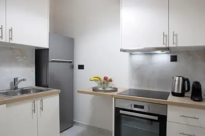 a kitchen with white cabinets and a sink at Warm & Coozy Residence in Athens