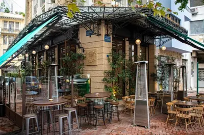 an outdoor patio with tables and chairs in front of a building at Metropolis A3 -Άνετη σουίτα in Athens