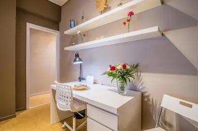 a room with a white desk with a vase of flowers at Glyfada's Central Apartment in Athens