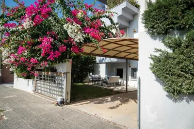 a garden with pink flowers on a white building at Pame Rentals - Cozy Glyfada Stay with Free Parking in Athens