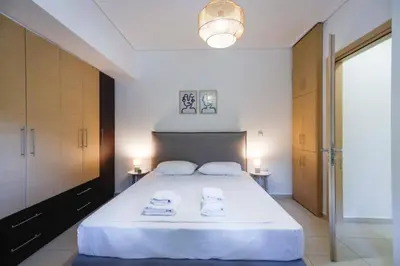 a bedroom with a large white bed with towels on it at Pame Rentals - Cozy Glyfada Stay with Free Parking in Athens