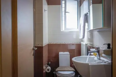 a bathroom with a toilet and a sink and a window at Pame Rentals - Cozy Glyfada Stay with Free Parking in Athens