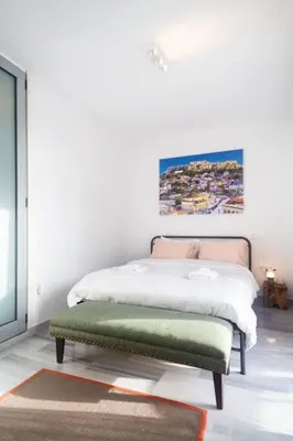a bedroom with a bed and a green ottoman at The Parthenon View in the Historical Center! in Athens