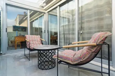 a rocking chair and a table on a balcony at The Parthenon View in the Historical Center! in Athens