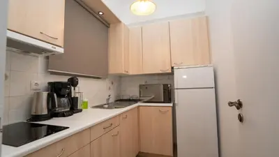 a kitchen with wooden cabinets and a white refrigerator at Quiet City Center Apt on a Pedestrian Street in Athens