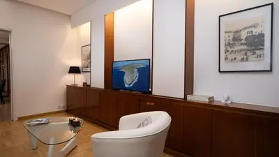 a living room with a white chair and a tv at Quiet City Center Apt on a Pedestrian Street in Athens