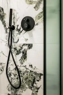a shower with a black shower head on a wall at Athens Luxury Rooms I in Athens