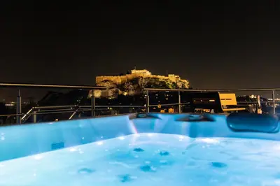 a bath tub with a view of a city at night at Majestic Penthouse Acropolis in Athens