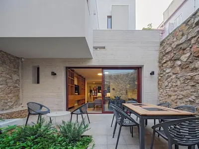 a patio with chairs and tables and a stone wall at A Neoclassical Mansion in Athens in Athens