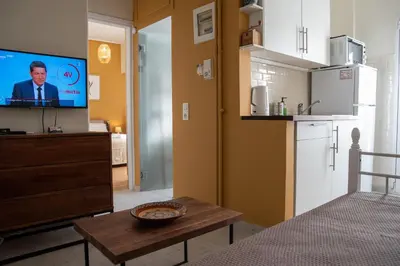 a living room with a tv and a kitchen at 3C's-Central, Cosy, Convenient to Airport 24/7 in Athens