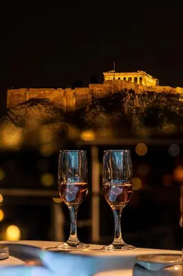 two glasses of wine sitting on a table with a city in the background at Majestic Acropolis-Lycabettus in Athens