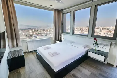 a bedroom with a white bed and large windows at Majestic Acropolis-Lycabettus in Athens