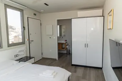 a bedroom with a white bed and a large window at Majestic Acropolis-Lycabettus in Athens