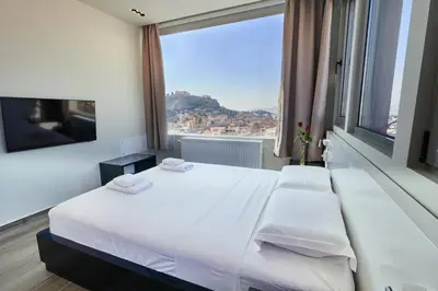 a bedroom with a large white bed and a large window at Majestic Acropolis-Lycabettus in Athens