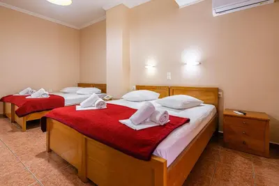 two beds in a room with red sheets and white towels at Faros II in Piraeus