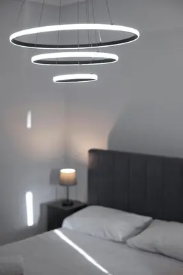 a bedroom with a bed and a large chandelier at Ella Suite Piraeus Stylish St, Balcony & Sea View in Piraeus