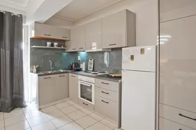 a kitchen with white cabinets and a white refrigerator at Ella Suite Piraeus Stylish St, Balcony & Sea View in Piraeus