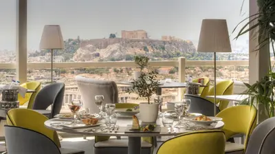 a restaurant with a table and chairs with a view ofhens at St George Lycabettus Lifestyle Hotel in Athens