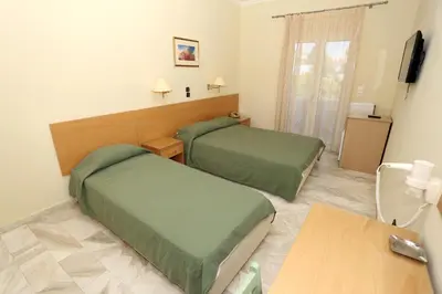 a hotel room with two beds and a table at Katerina Hotel in Agia Marina Aegina