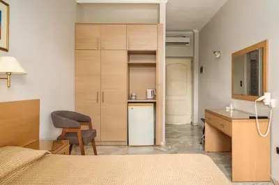 a room with a bed and a desk and a kitchen at Katerina Hotel in Agia Marina Aegina