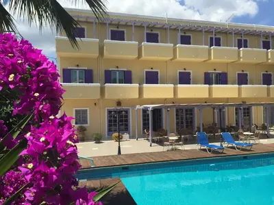 a hotel with a swimming pool and purple flowers at Katerina Hotel in Agia Marina Aegina