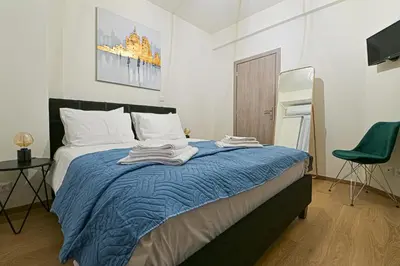 a bedroom with a bed with a blue blanket and a chair at Areos Comfort Living Apartment - Alexandras Ave 72 in Athens