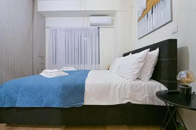 a bedroom with a bed with a blue blanket and white pillows at Areos Comfort Living Apartment - Alexandras Ave 72 in Athens