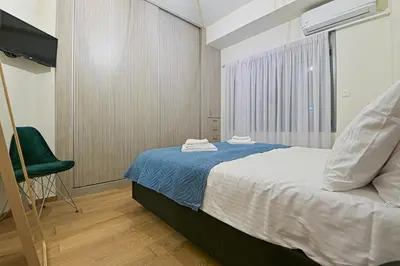 a bedroom with a bed and a green chair at Areos Comfort Living Apartment - Alexandras Ave 72 in Athens