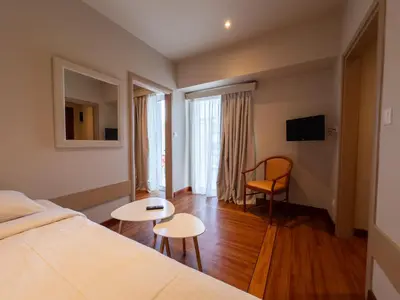 a bedroom with a bed and two tables and a chair at Anemoni Piraeus Hotel in Piraeus